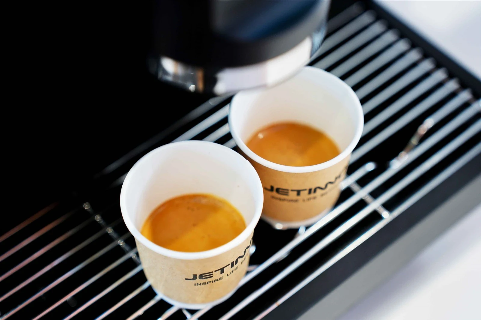 Dos espressos preparados en una máquina Jetinno, con detalle de la crema y los acabados de acero
