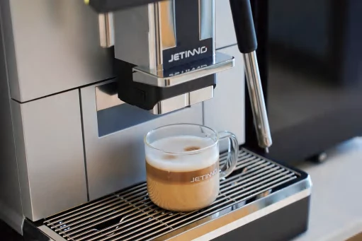 Una máquina Jetinno prepara un café con leche en una taza de cristal